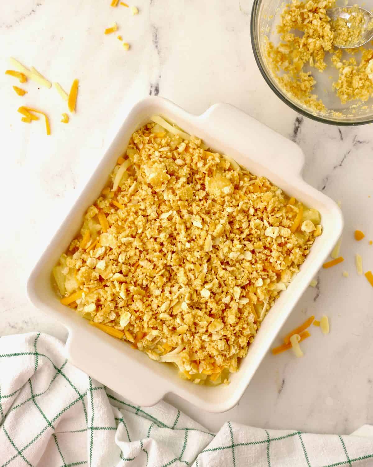 Crushed Ritz crackers topping casserole ingredients in a square baking dish. 