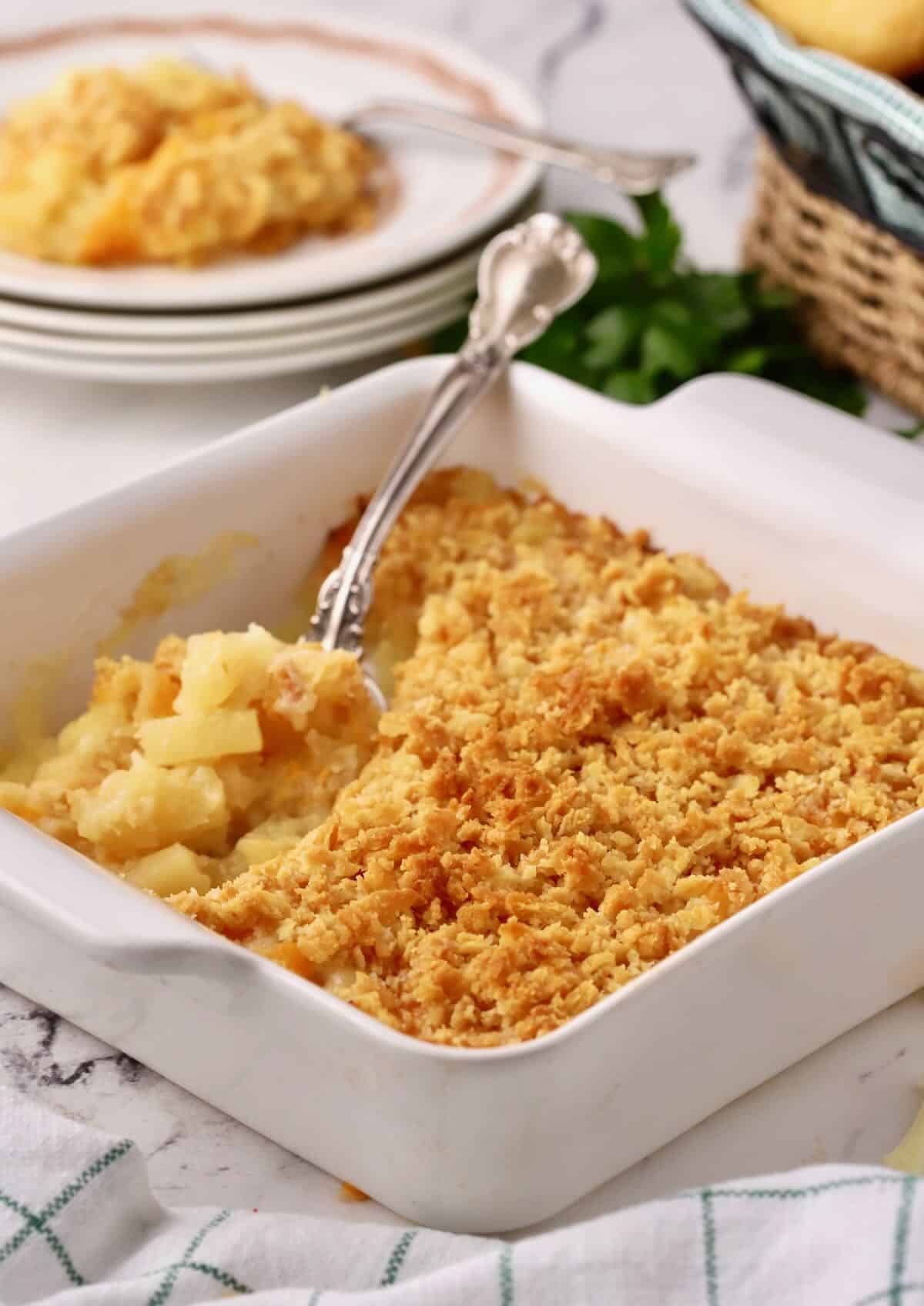 A baking dish with pineapple cheese casserole.