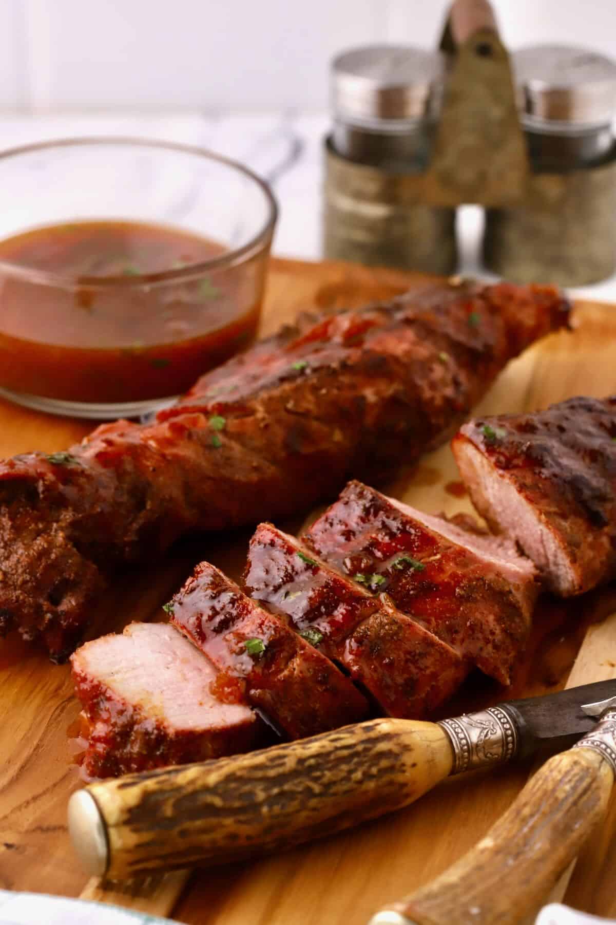 Sliced pork tenderloins on a cutting board with a knife and fork. 