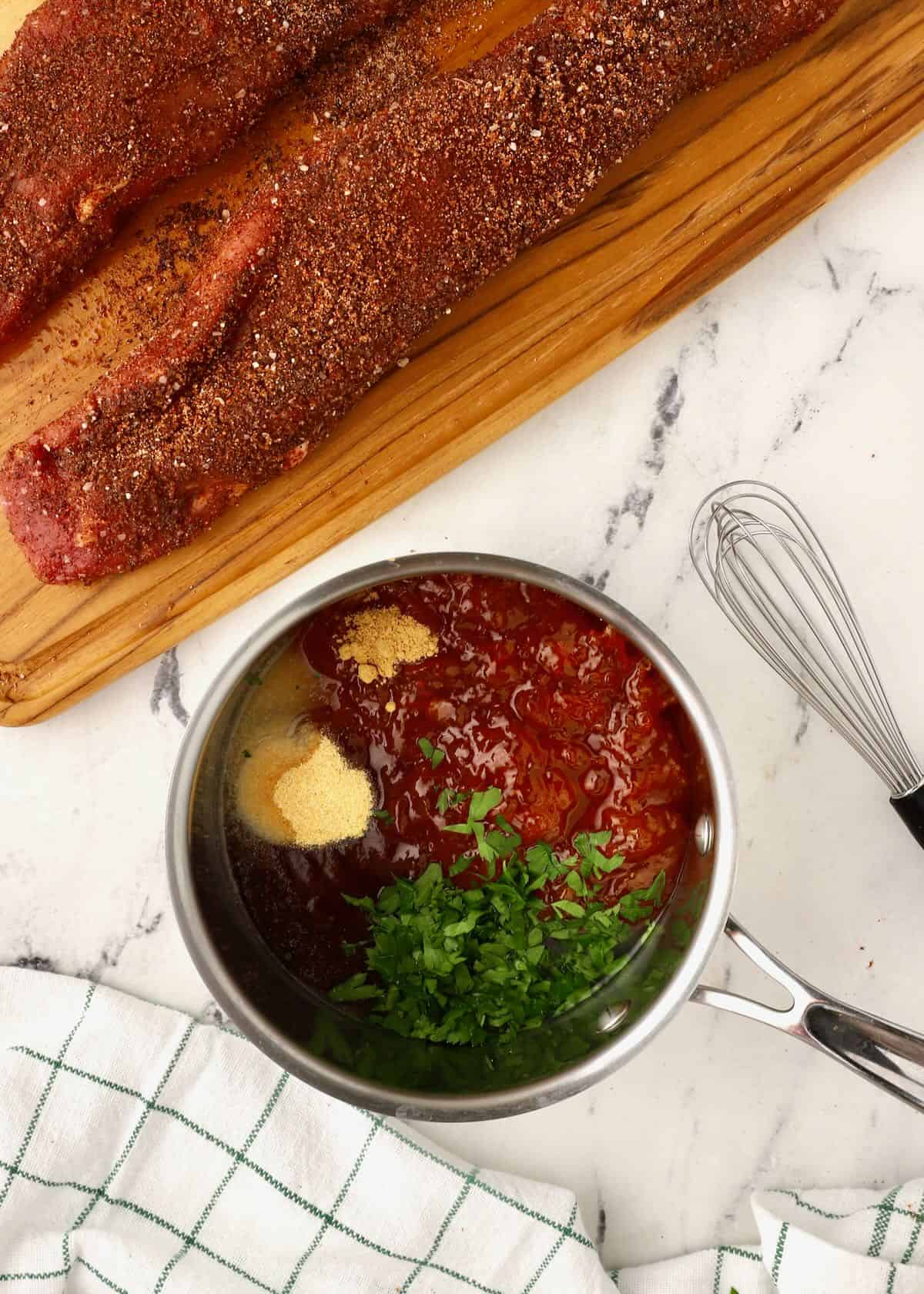 A small sauce pan with apricot preserves, barbecue sauce and  chopped parsley. 