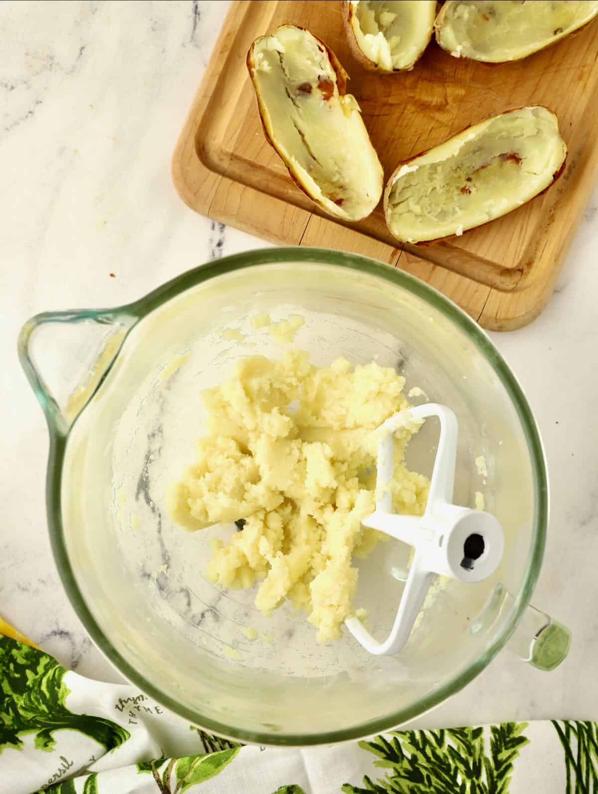 Mashed potatoes in a bowl with a paddle mixer attachment. 