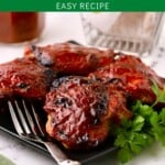 Pinterest pin showing four BBQ chicken thighs on a black plate.