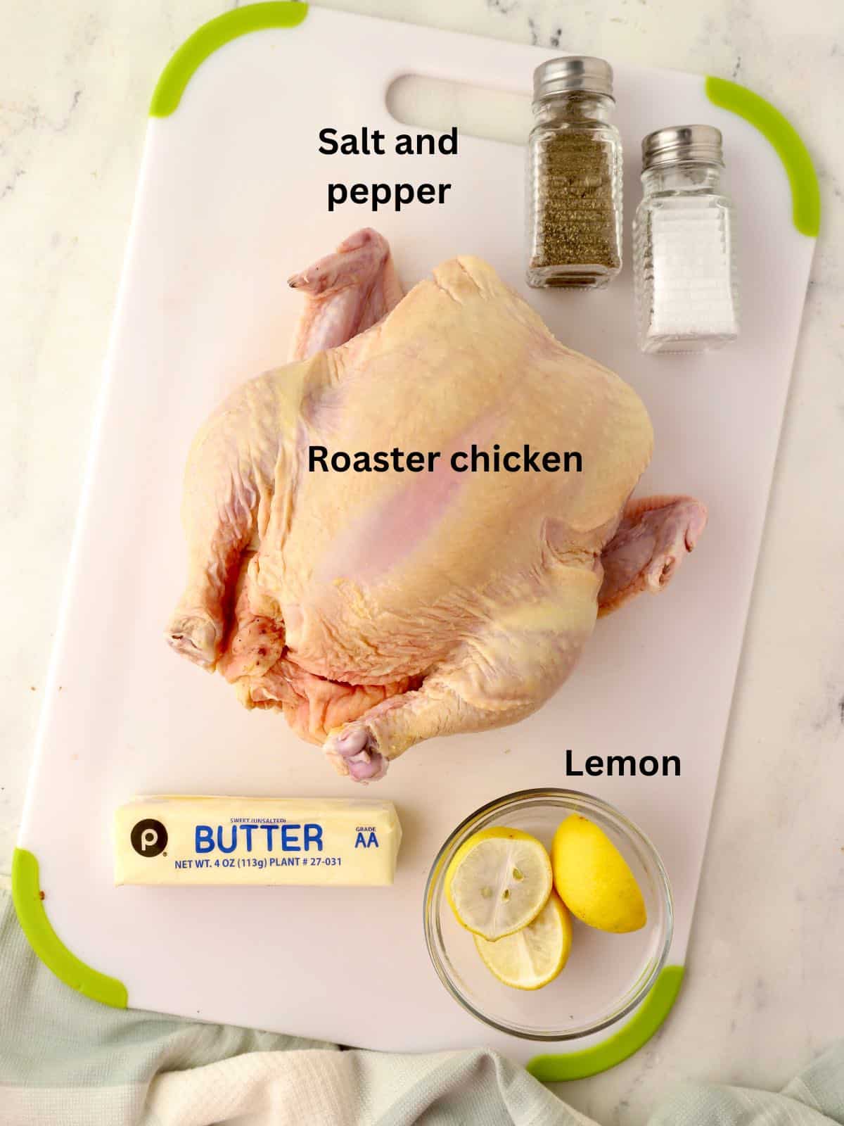 A whole chicken on a cutting board with salt and pepper shakers and a stick of butter. 