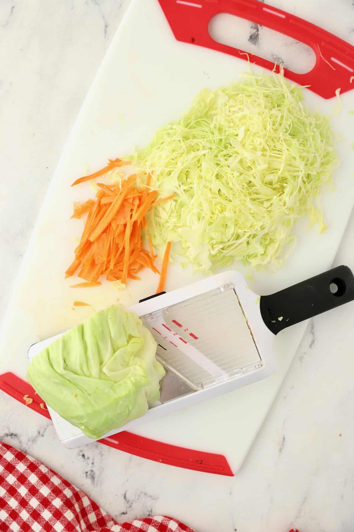 Using a mandoline to grate cabbage and carrots. 
