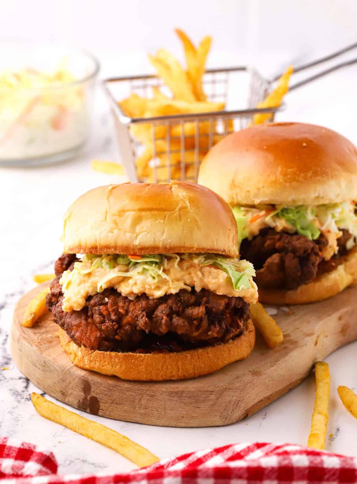 Two fried chicken burgers topped with pimento cheese and coleslaw.