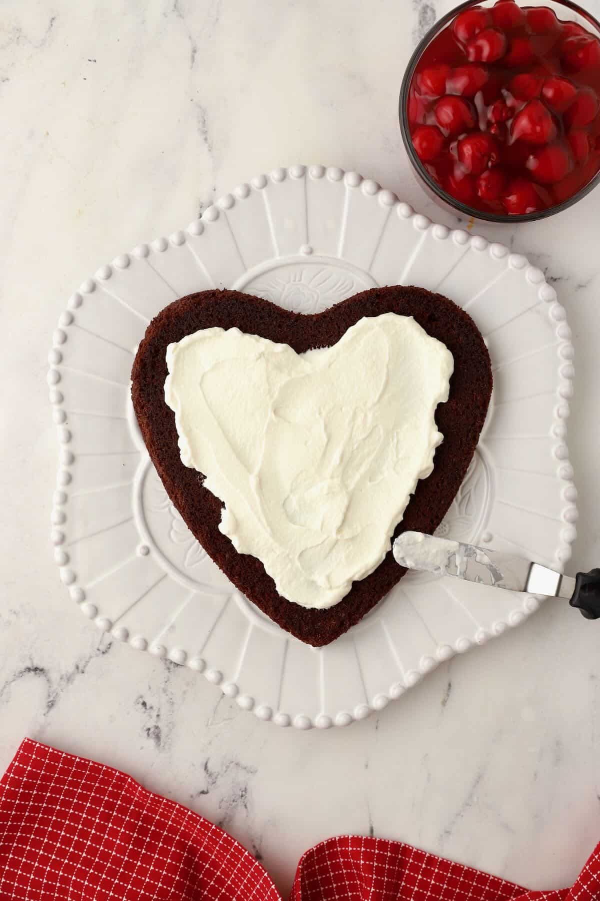 A heart shaped chocolate cake topped with whipped cream. 