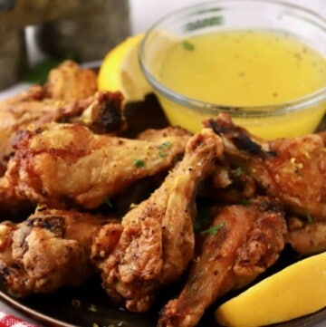 Lemon pepper chicken wings on a plate with a dipping sauce.