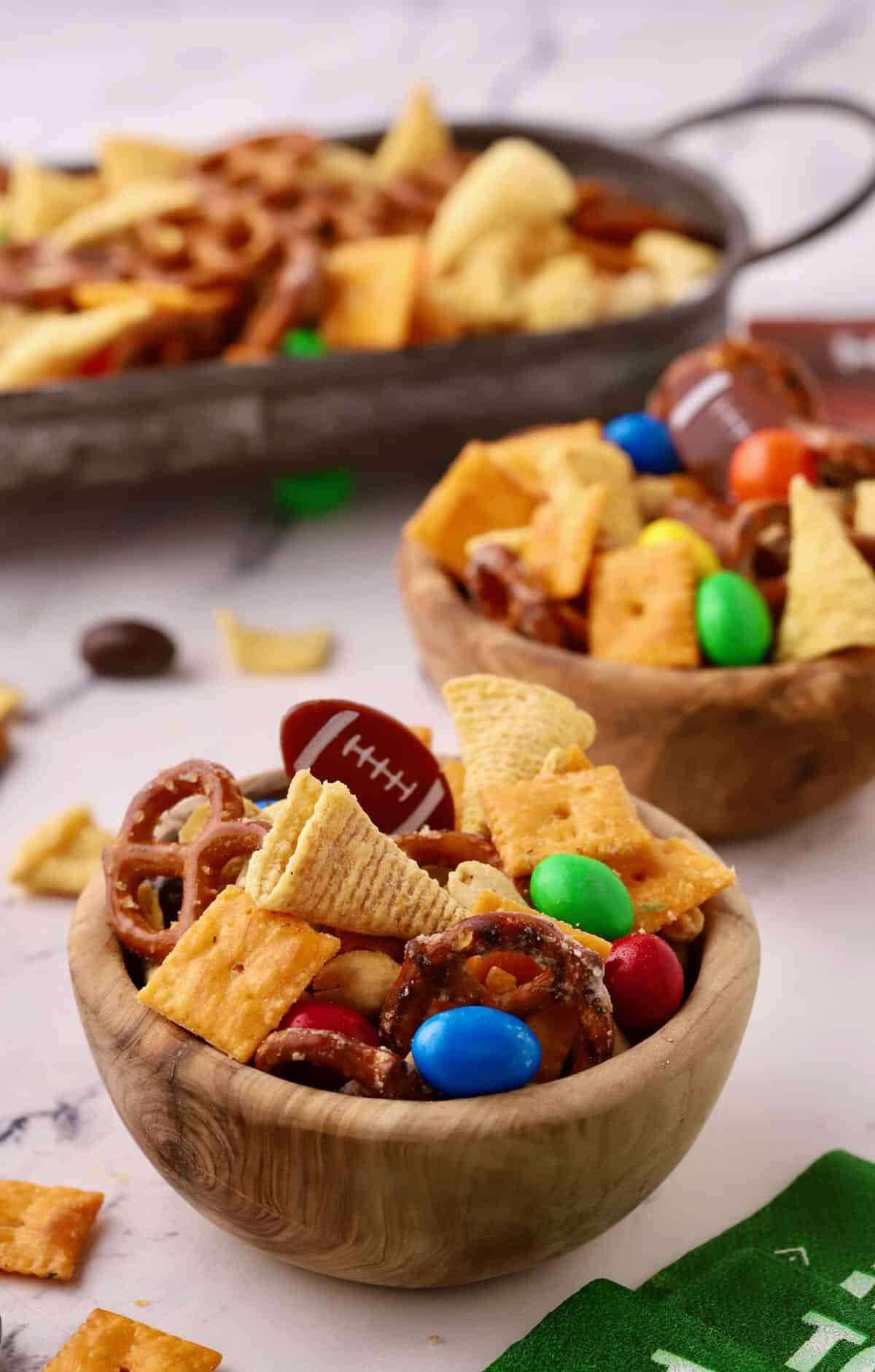 Two bowls of snack mix with Cheez-its, Bugles, and Pretzels.