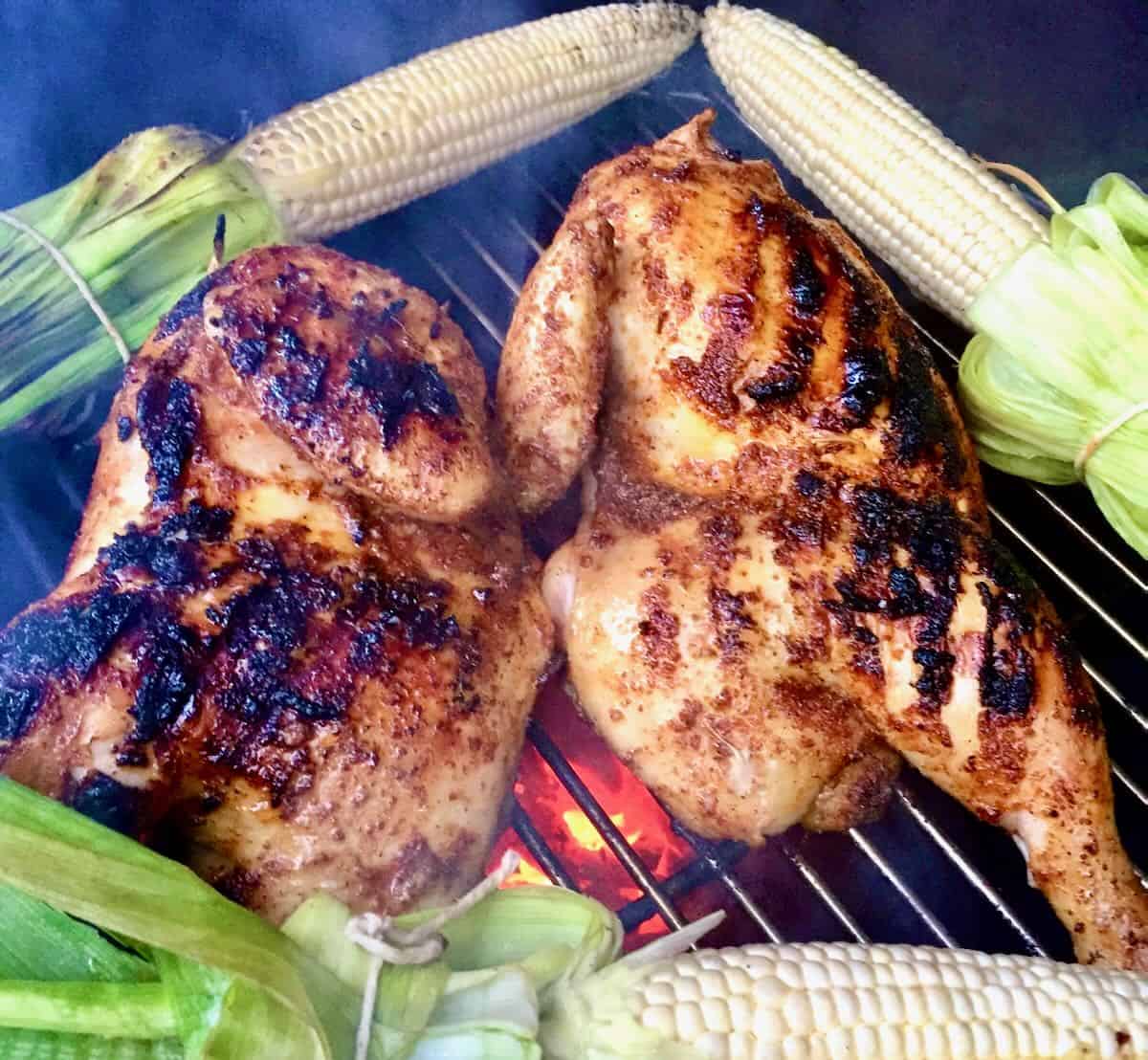 Two chicken halves cooking on a grill. 