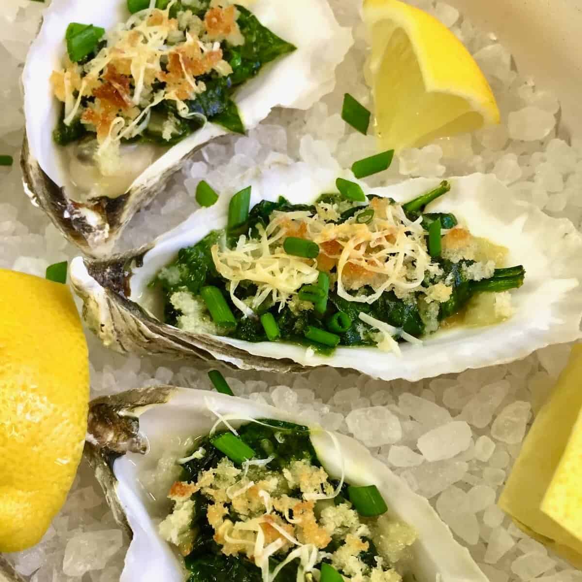 Three oysters Rockefeller on a bed of rock salt.