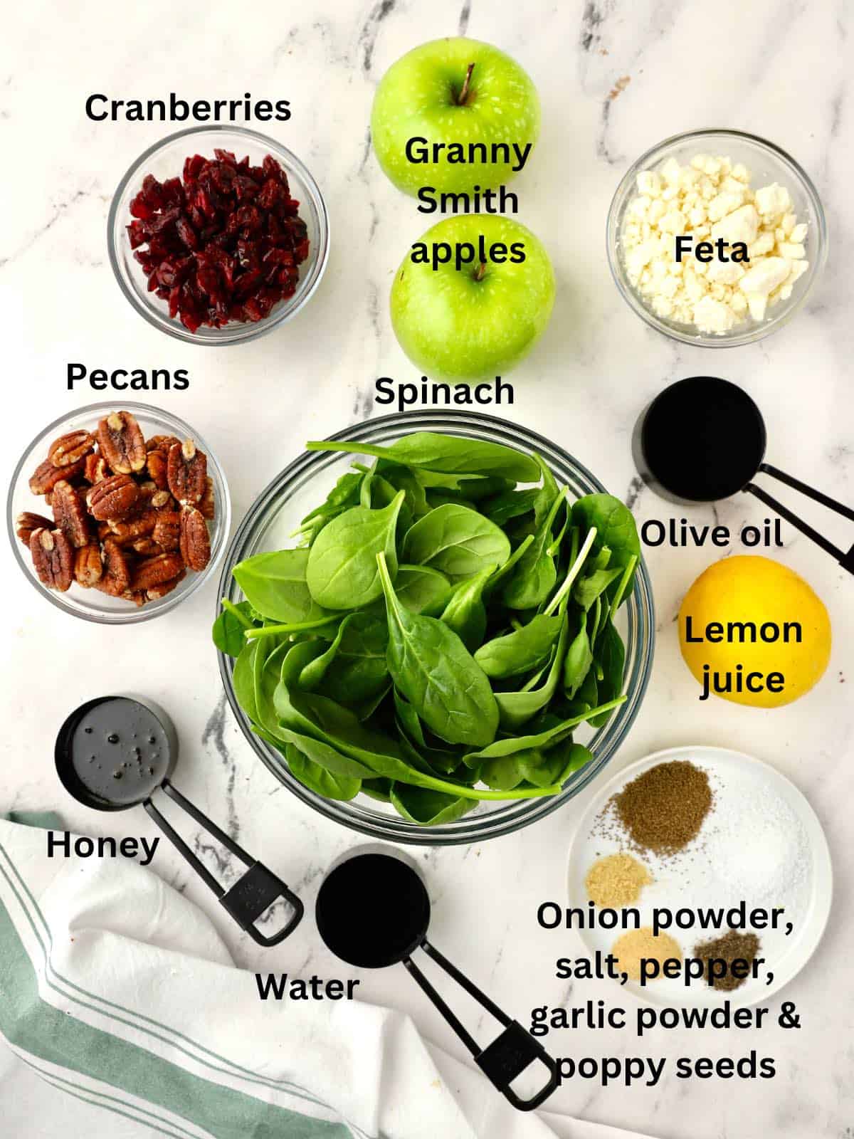 A large bowl of spinach leaves, apples, pecans and other ingredients to make a spinach salad. 