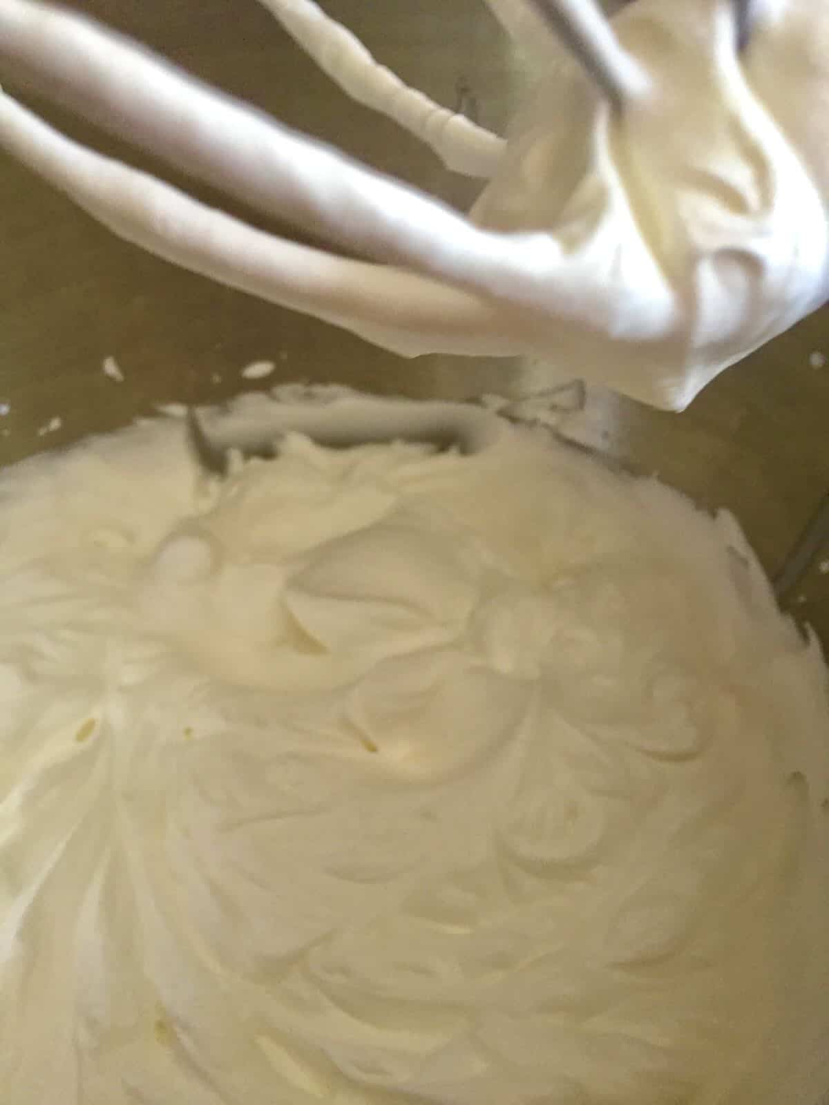 Whipped cream in a bowl with a beater. 