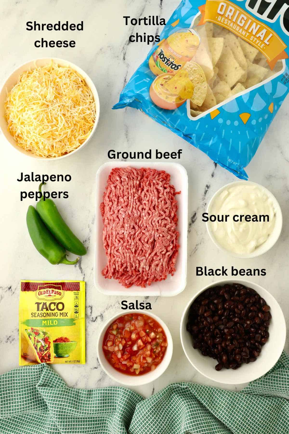 Ingredients to make nachos including ground beef, cheese, and a bag of tortilla chips. 