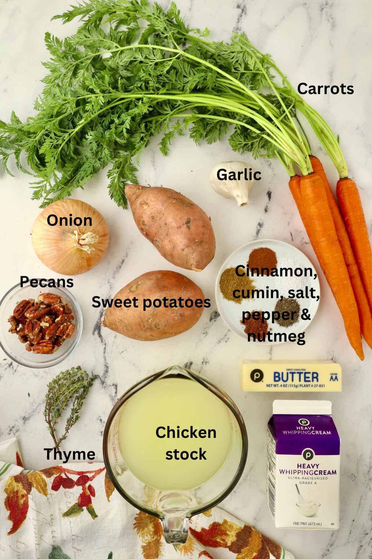 Ingredients for soup including sweet potatoes, carrots and chicken stock. 