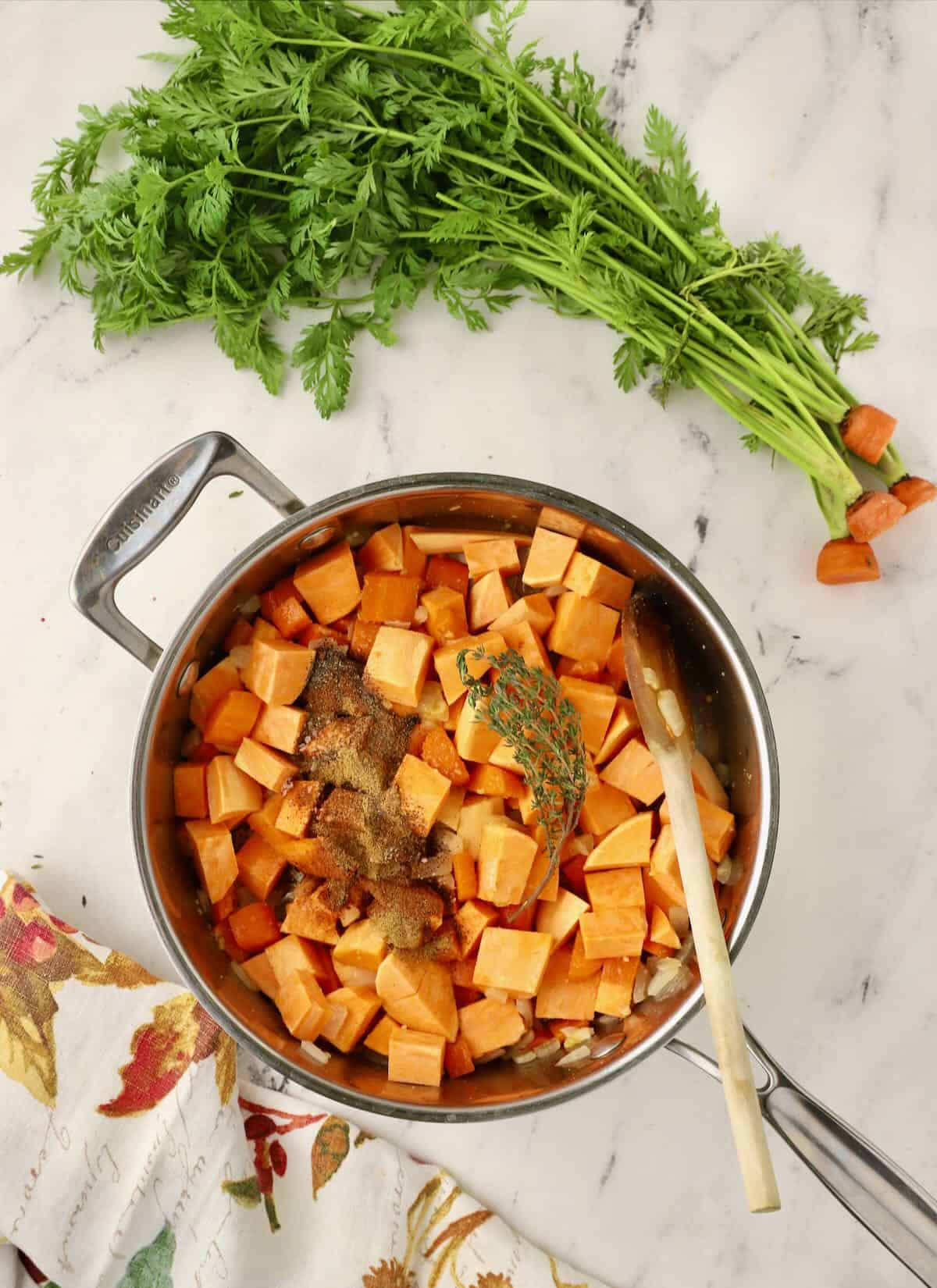 Chopped sweet potatoes, carrots, and onions cooking in a stock pot. 