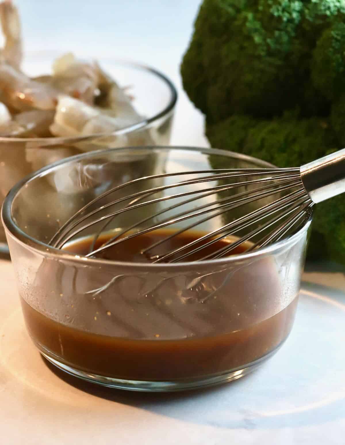 A clear glass bowl with ingredients to make a stir-fry sauce. 