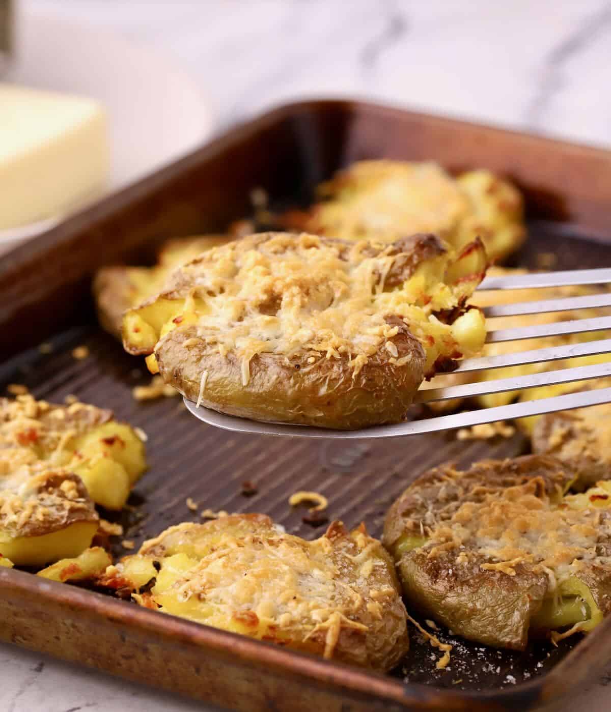 Lifting up a cooked smashed potato with a spatula.  