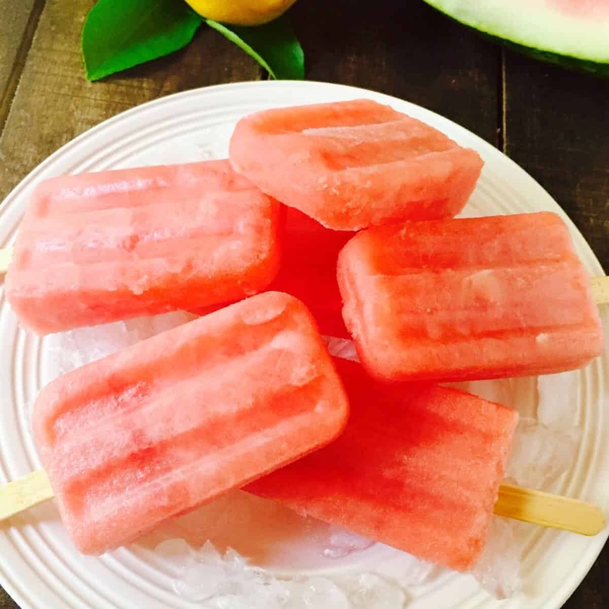 Watermelon popsicles on a plate of ice to keep them cold.