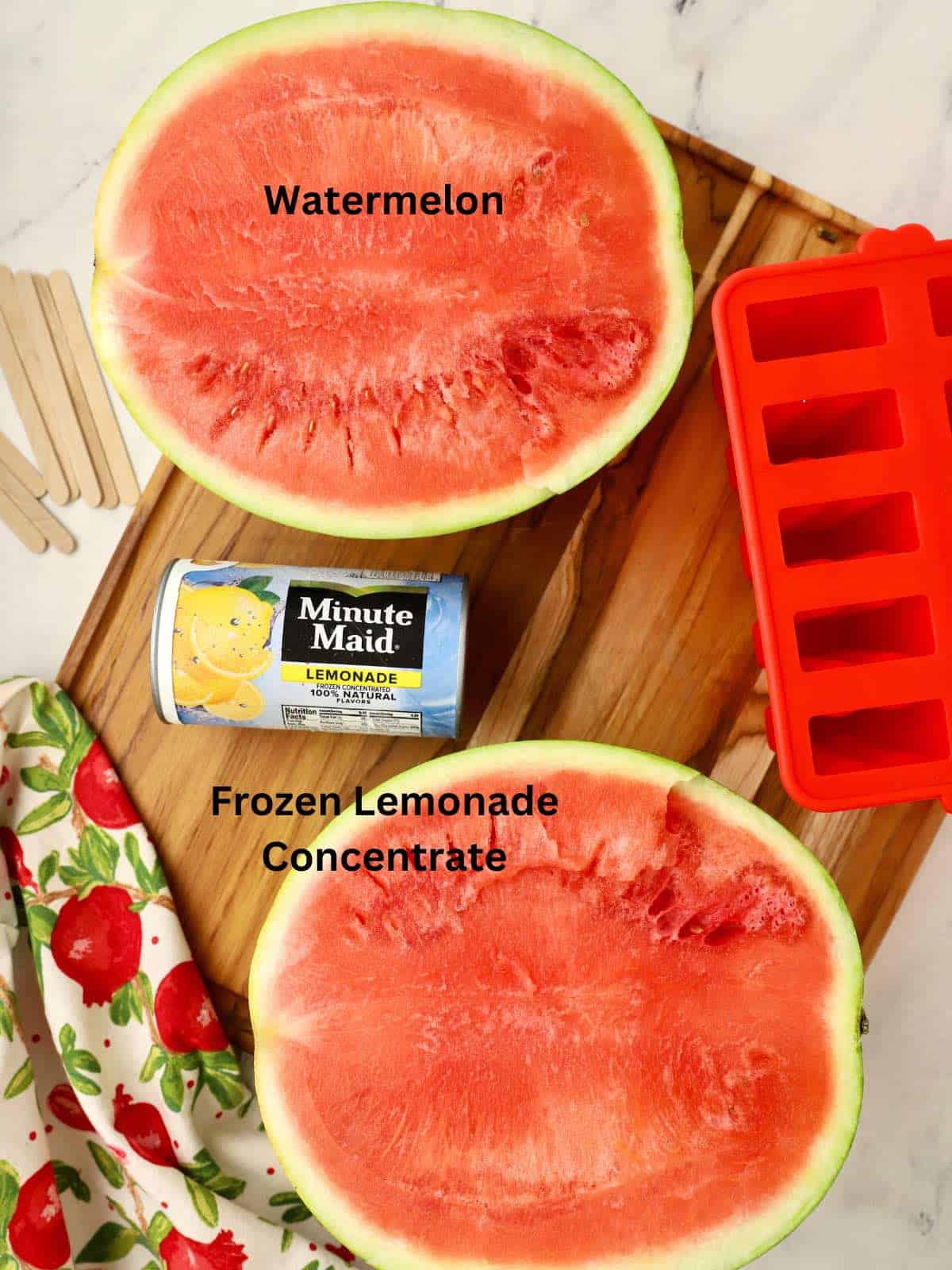 Watermelon cut in half on a cutting board along with a can of frozen lemonade concentrate.