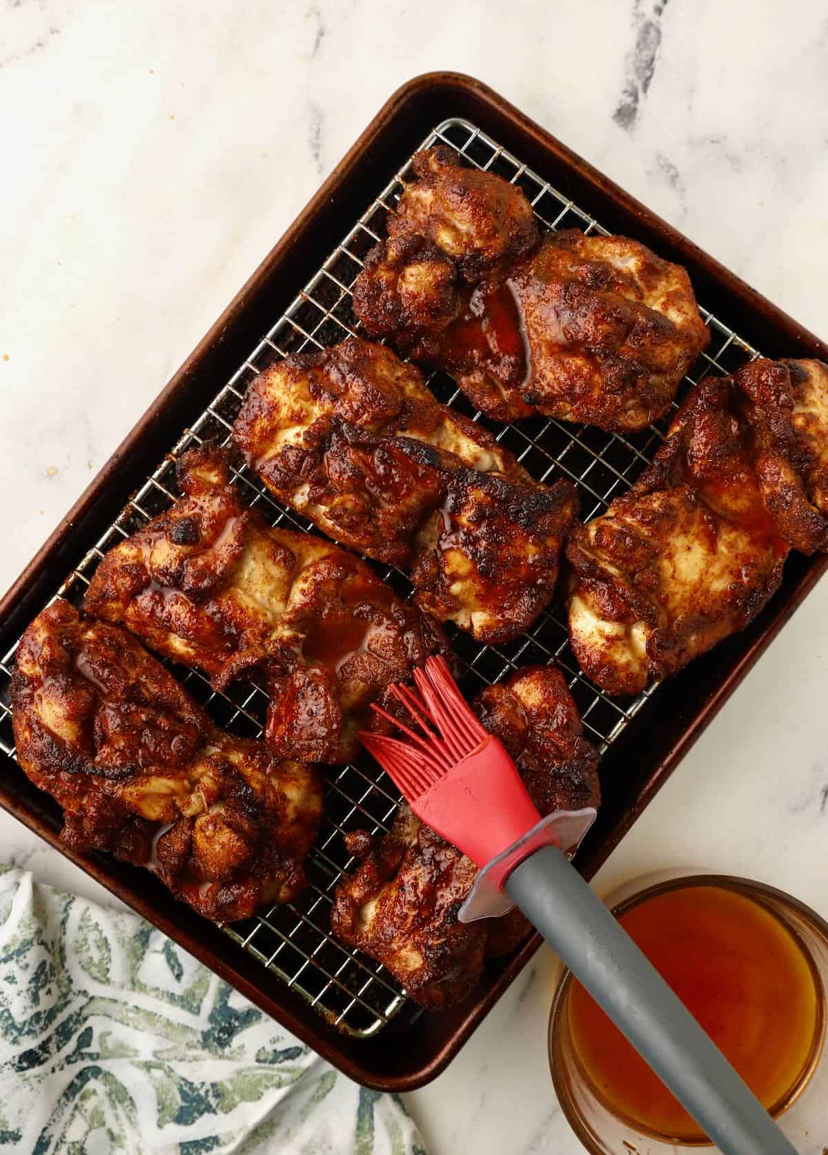 Using a pastry brush to coat chicken pieces with a honey glaze. 