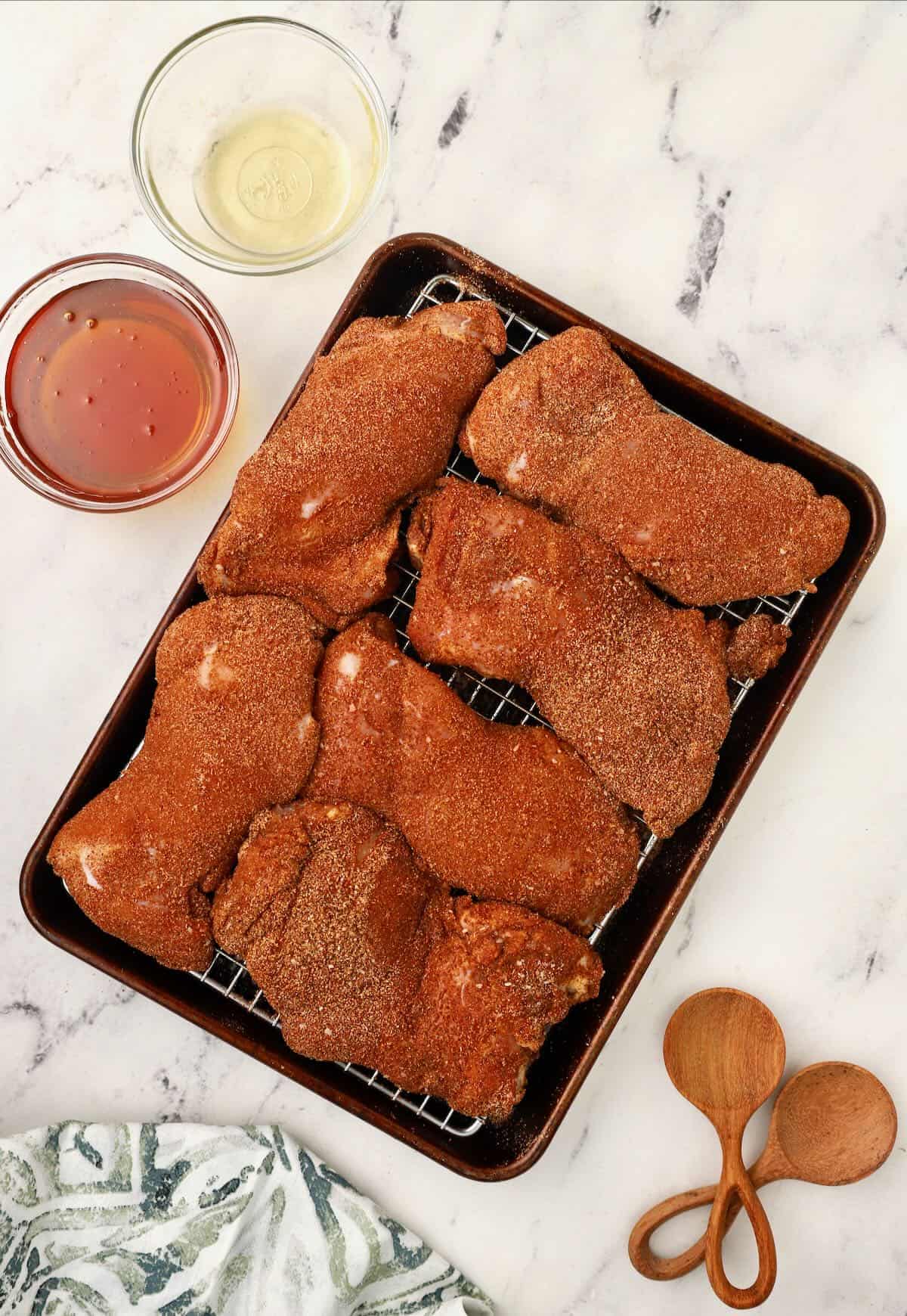 Chicken thighs coated with dry rub on a wire cooking rack. 