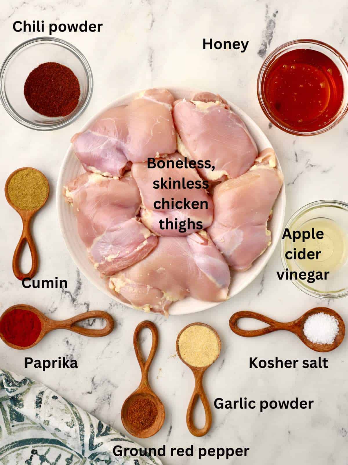 Ingredients for broiled chicken thighs including spices, honey, and apple cider vinegar. 