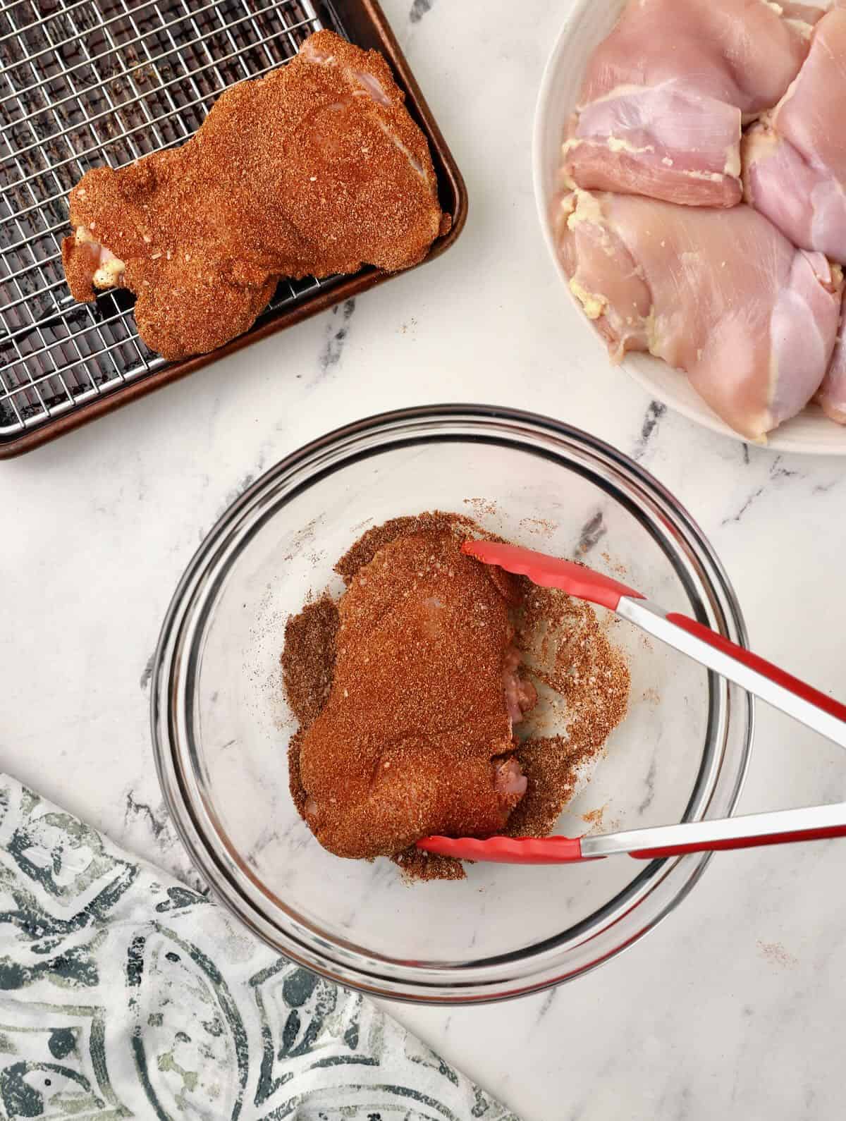 Coating chicken thighs with a dry rub in a bowl. 