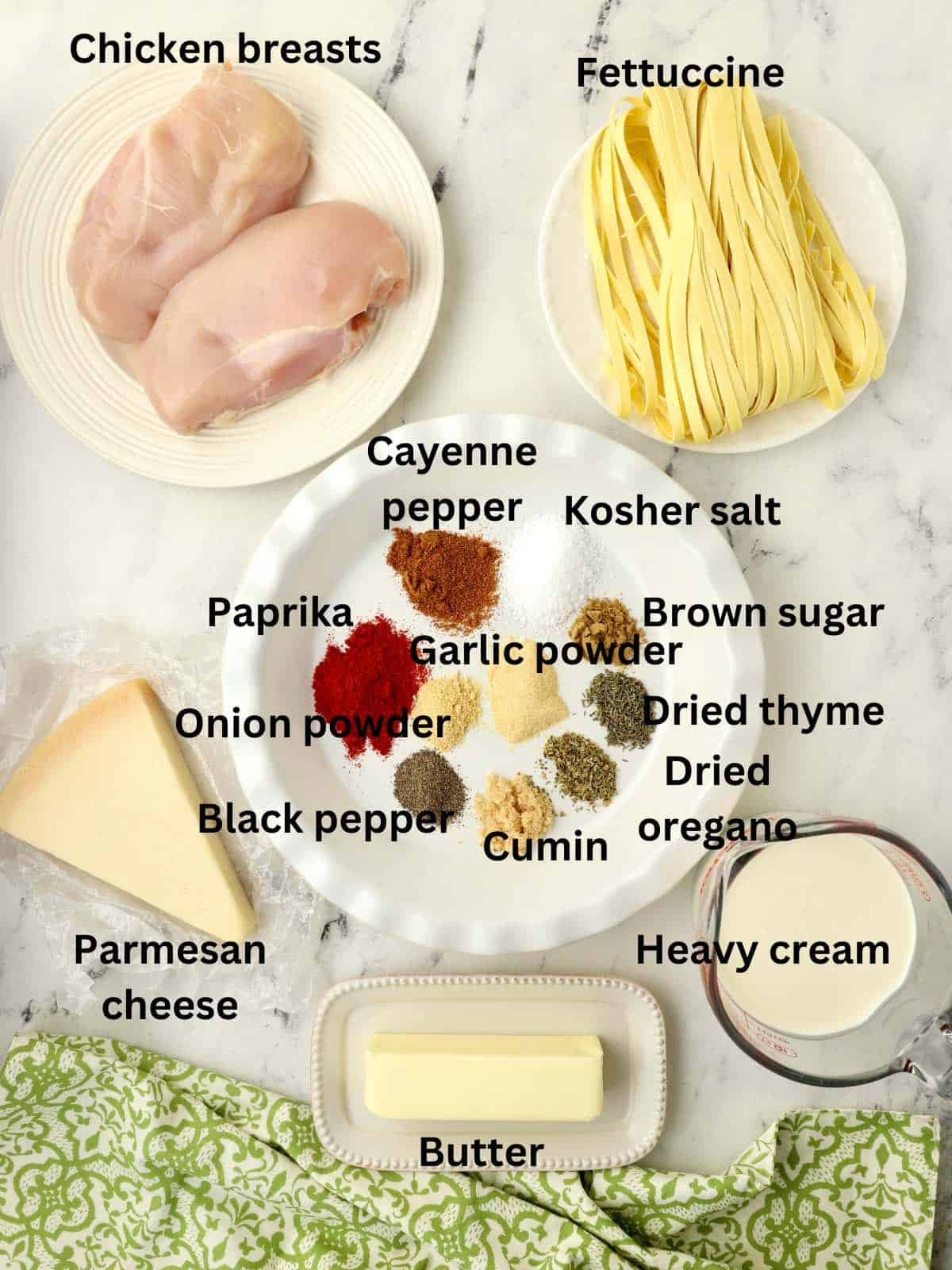 Ingredients for blackening seasonings, raw chicken breasts, fettuccine and a block of parmesan cheese. 