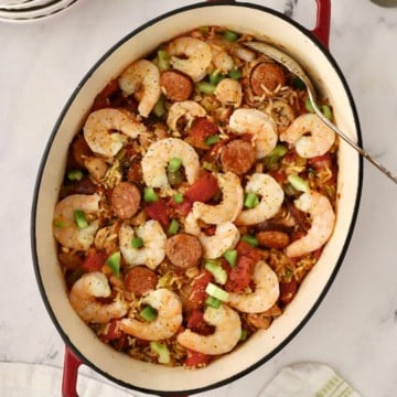 A Dutch oven full of Seafood Jambalaya topped with shrimp.