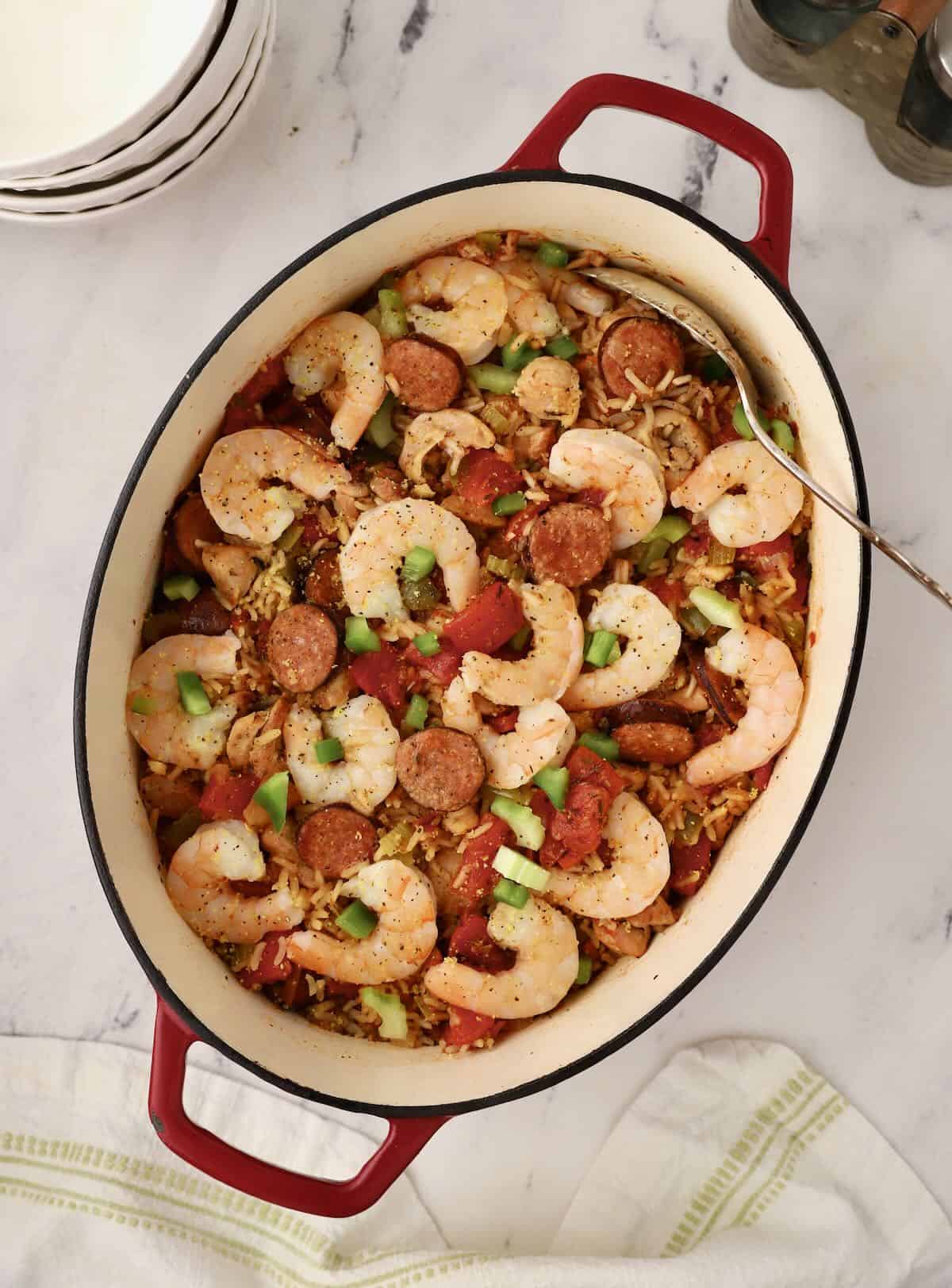 A dutch oven full of seafood jambalaya topped with shrimp. 