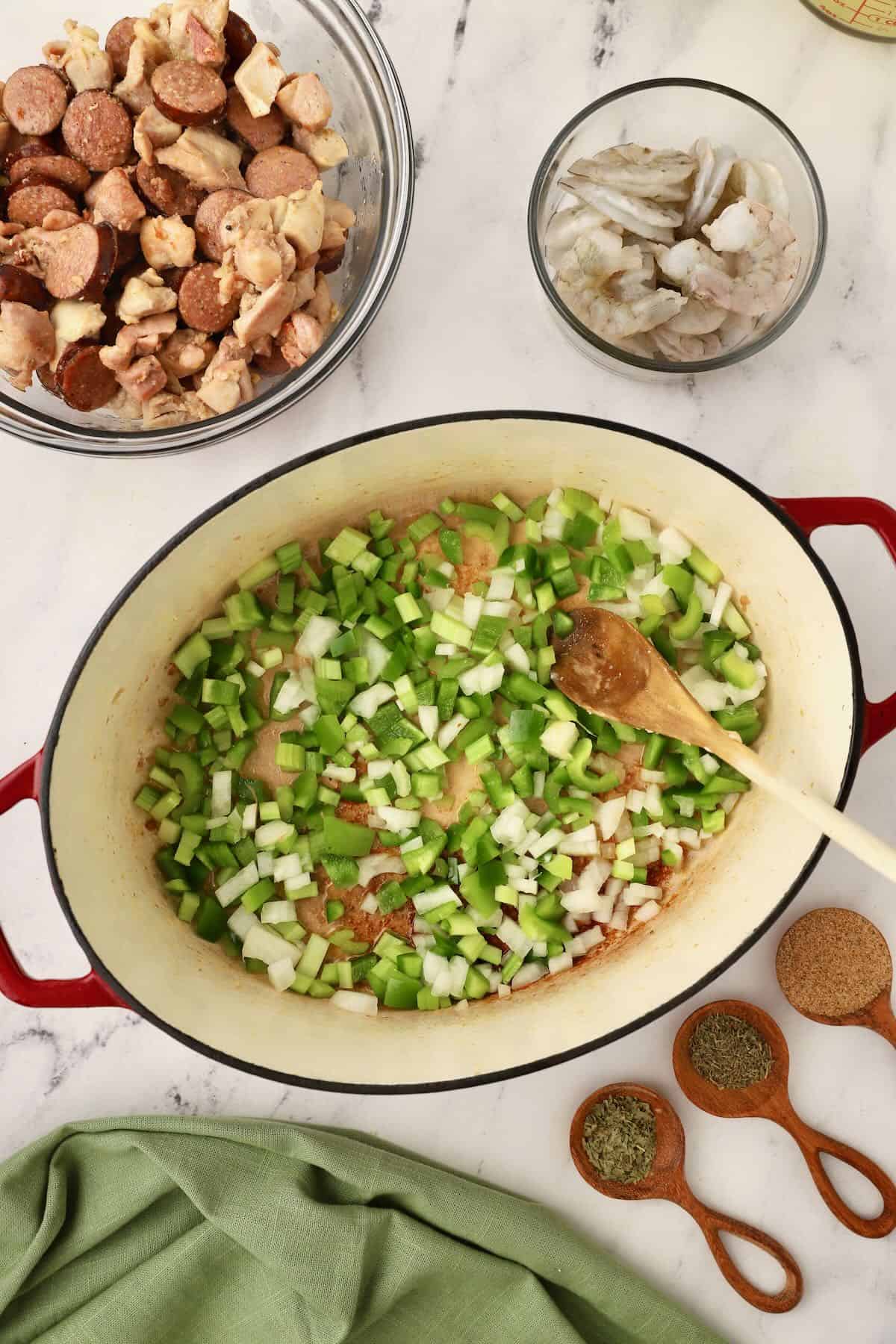 Chopped onion, bell pepper, and celery cooking in a Dutch oven. 