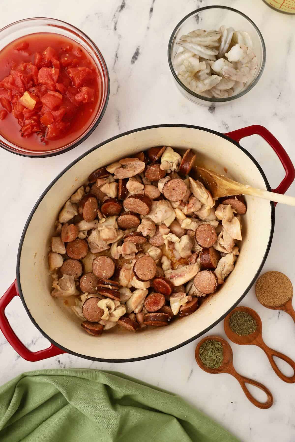 Andouille sausage and chicken cooking in a Dutch oven. 