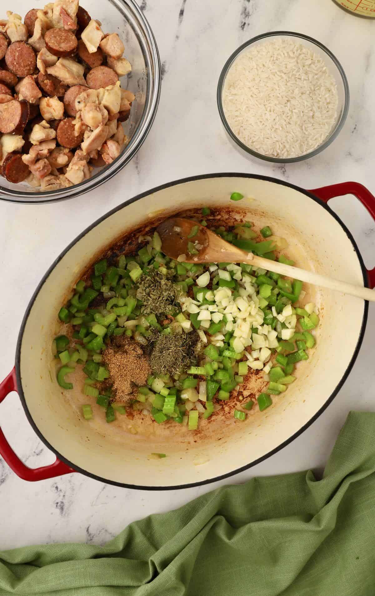 Creole seasoning added to celery, bell pepper and onion cooking in a pan. 