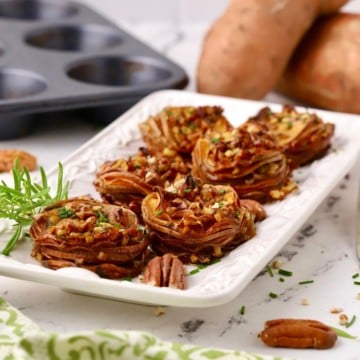 Baked Sweet Potato Slices stacked on a white platter.