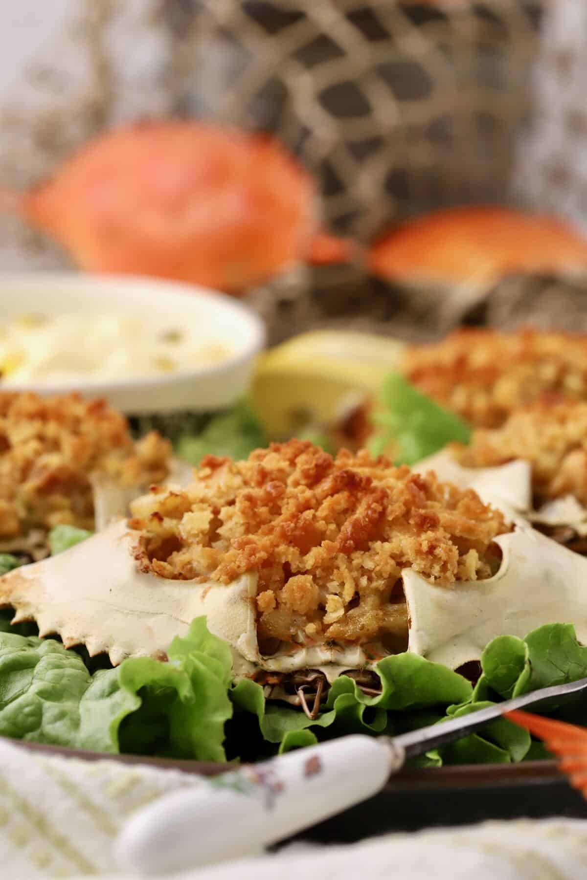 Deviled crab stuffed in a blue crab shell on a plate of lettuce leaves. 
