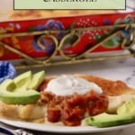 A serving of sour cream chicken enchilada casserole on a white plate garnished with avocado slices.
