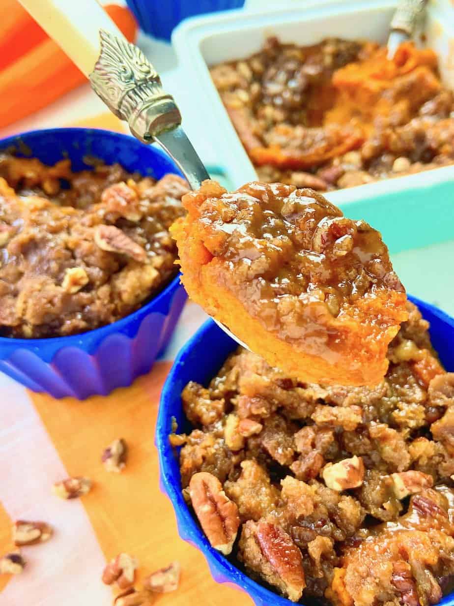 A blue casserole dish with a carrot souffle topped with pecans. 