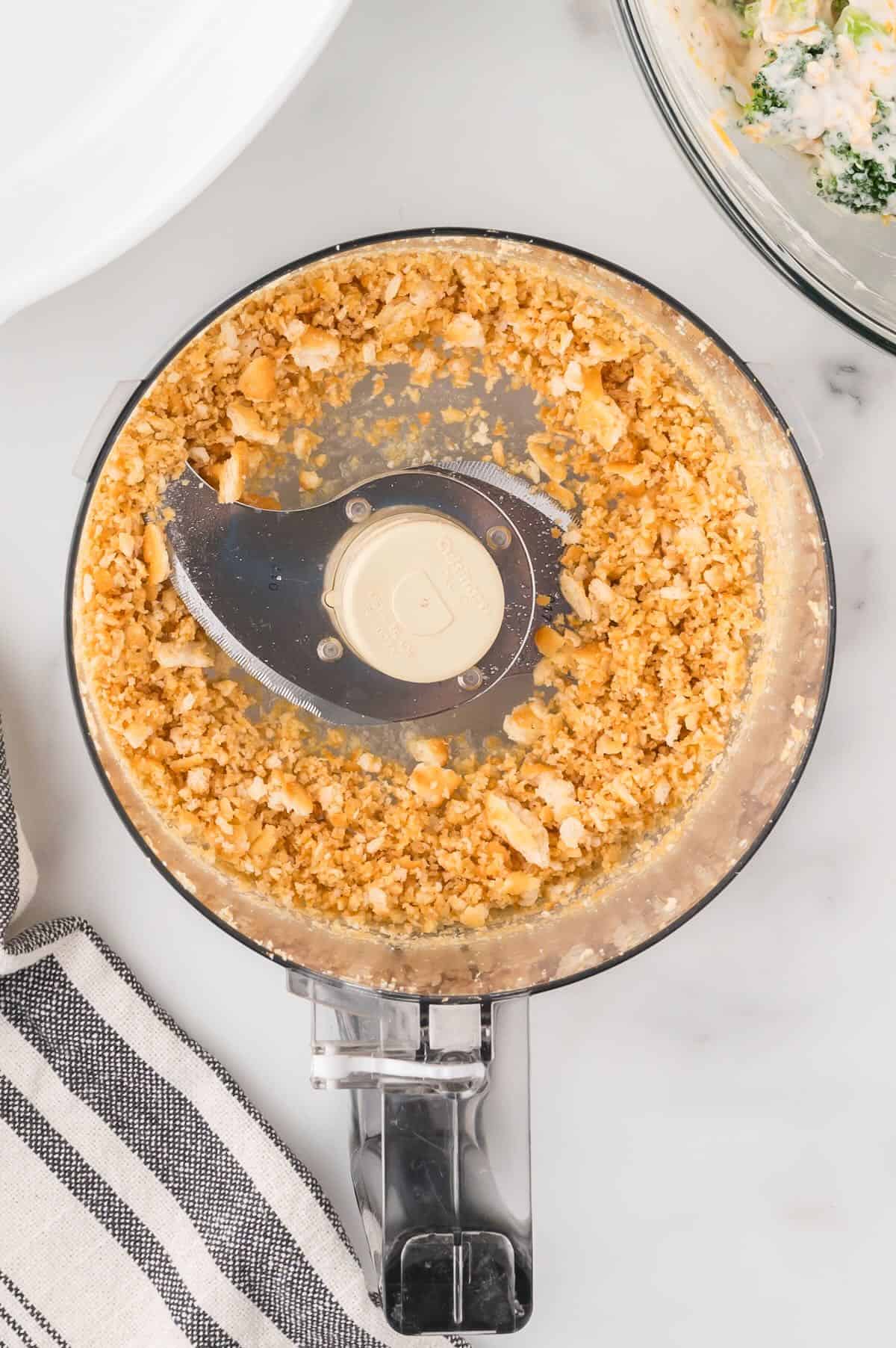Ritz crackers in a food processor are being crushed. 