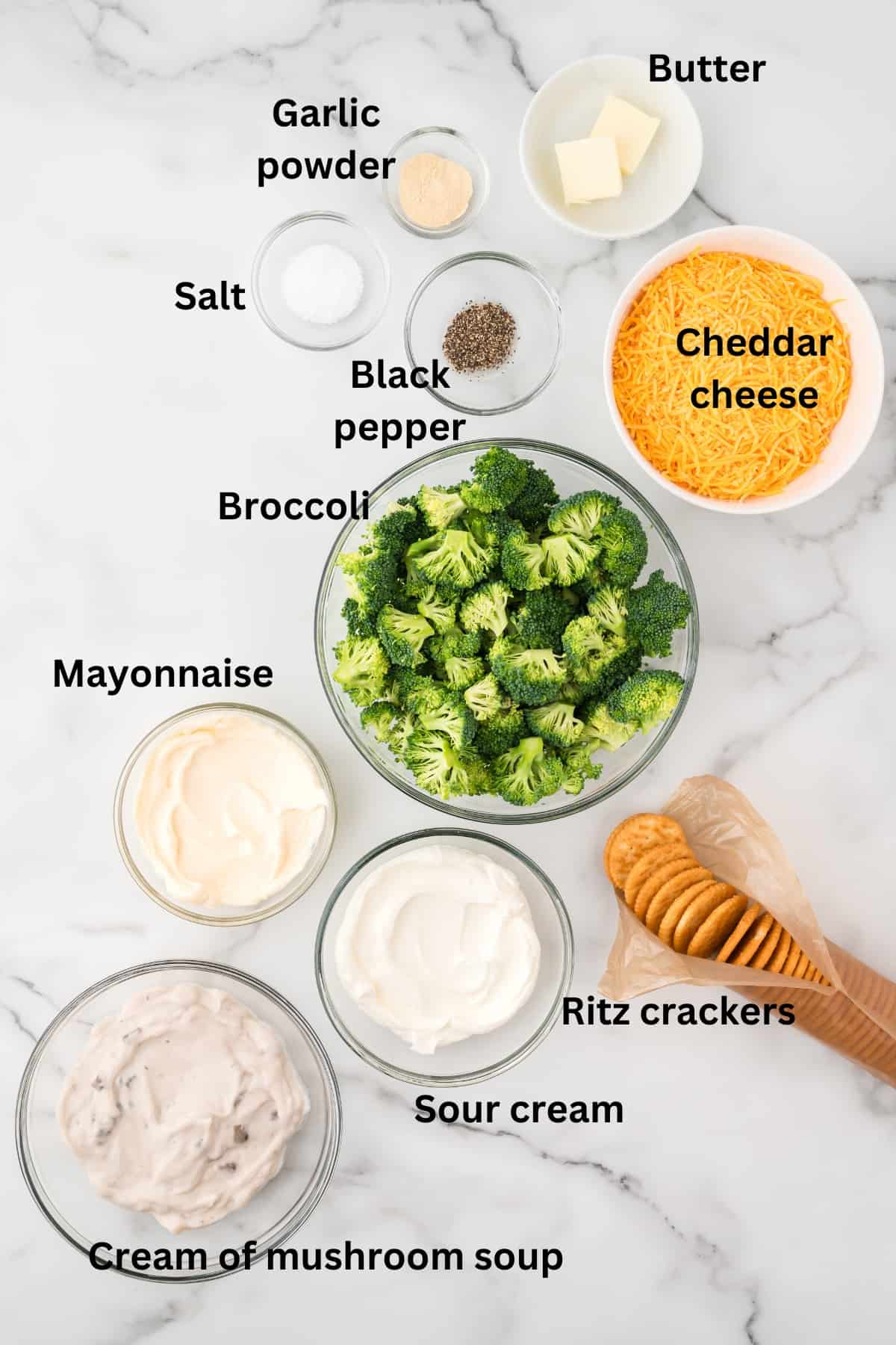 Ingredients for broccoli cheese casserole include broccoli florets, shredded cheese, and a bowl of sour cream. 