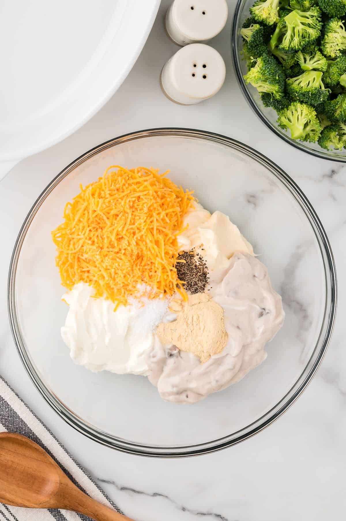 Mayonnaise, cream of mushroom soup, and other ingredients in a clear glass bowl. 