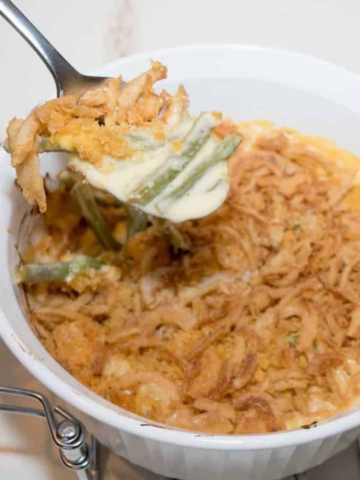 A white casserole dish with a green bean casserole topped with fried onions. 