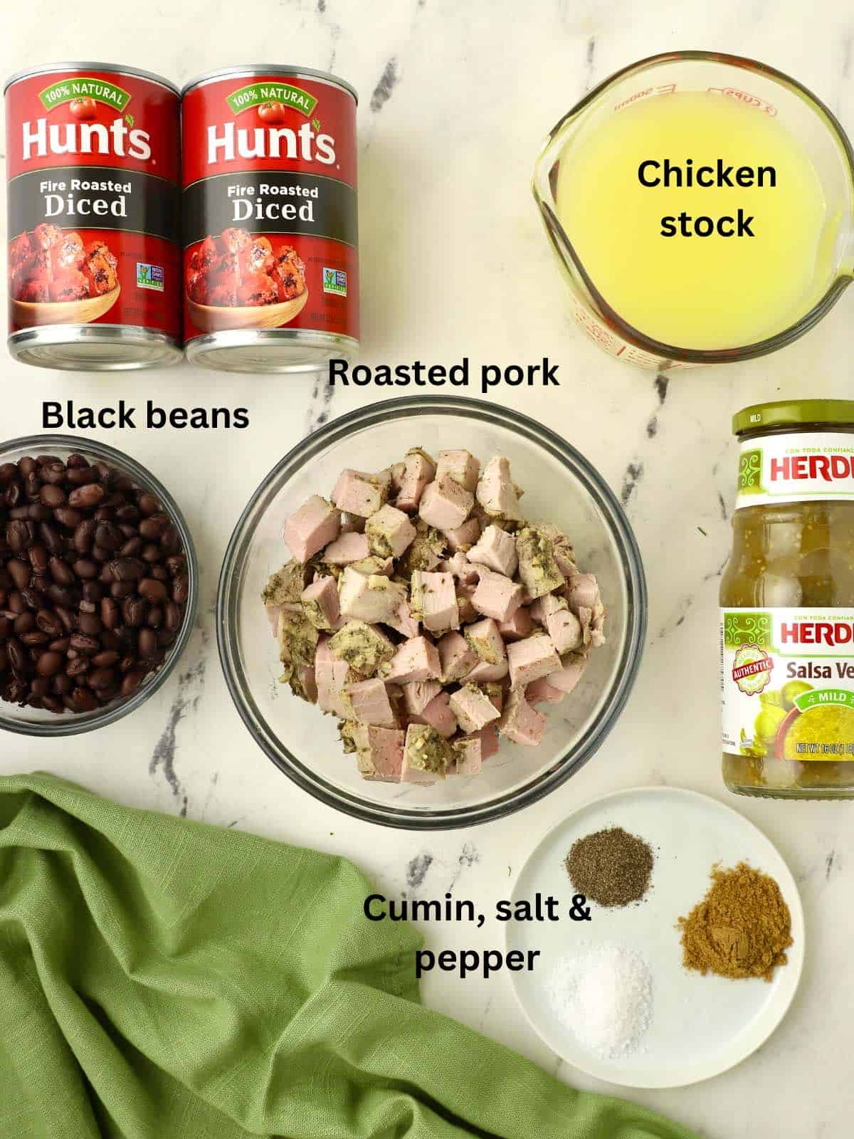 A bowl of cooked pork, two cans of diced tomatoes and a jar of salsa verde. 