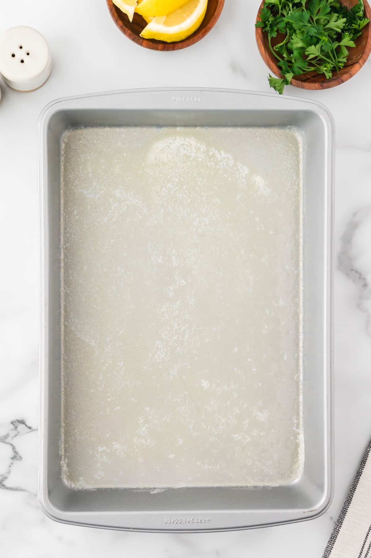 A metal baking pan with melted butter. 
