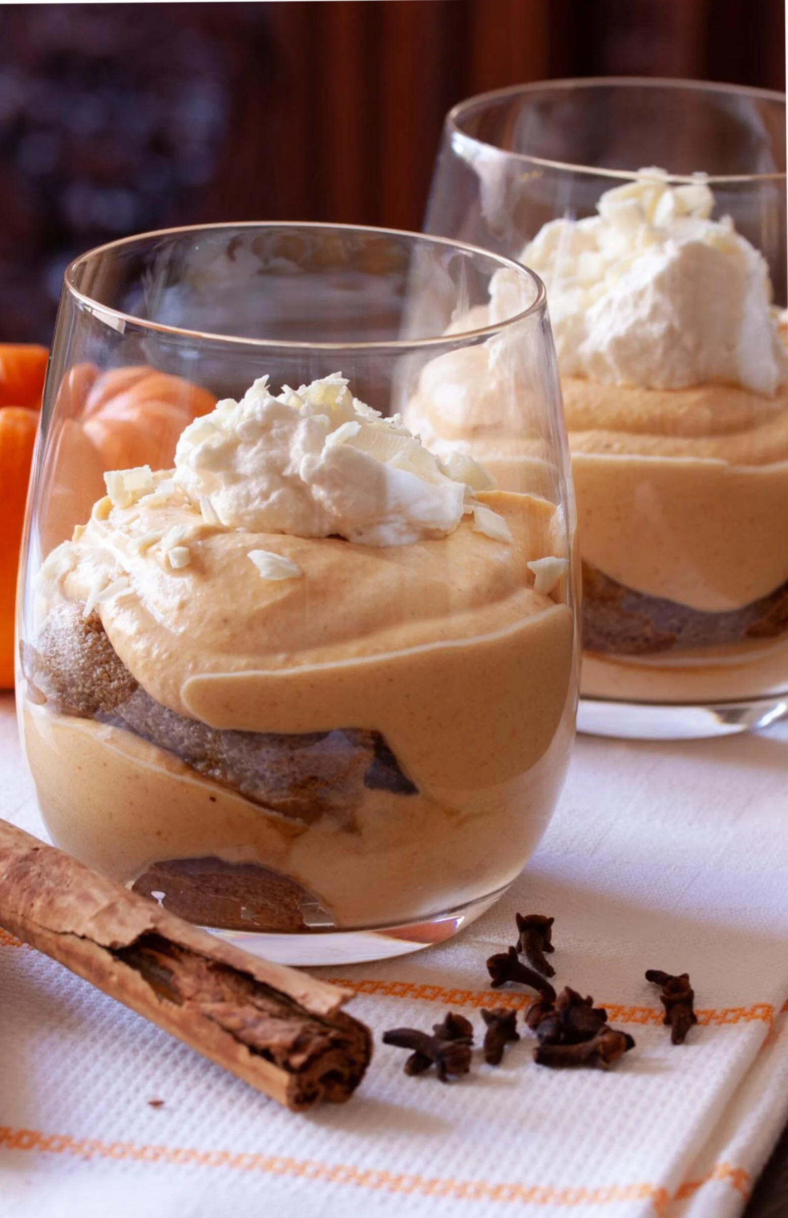 Pumpkin tiramisu in individual glass jars, topped with whipped cream. 