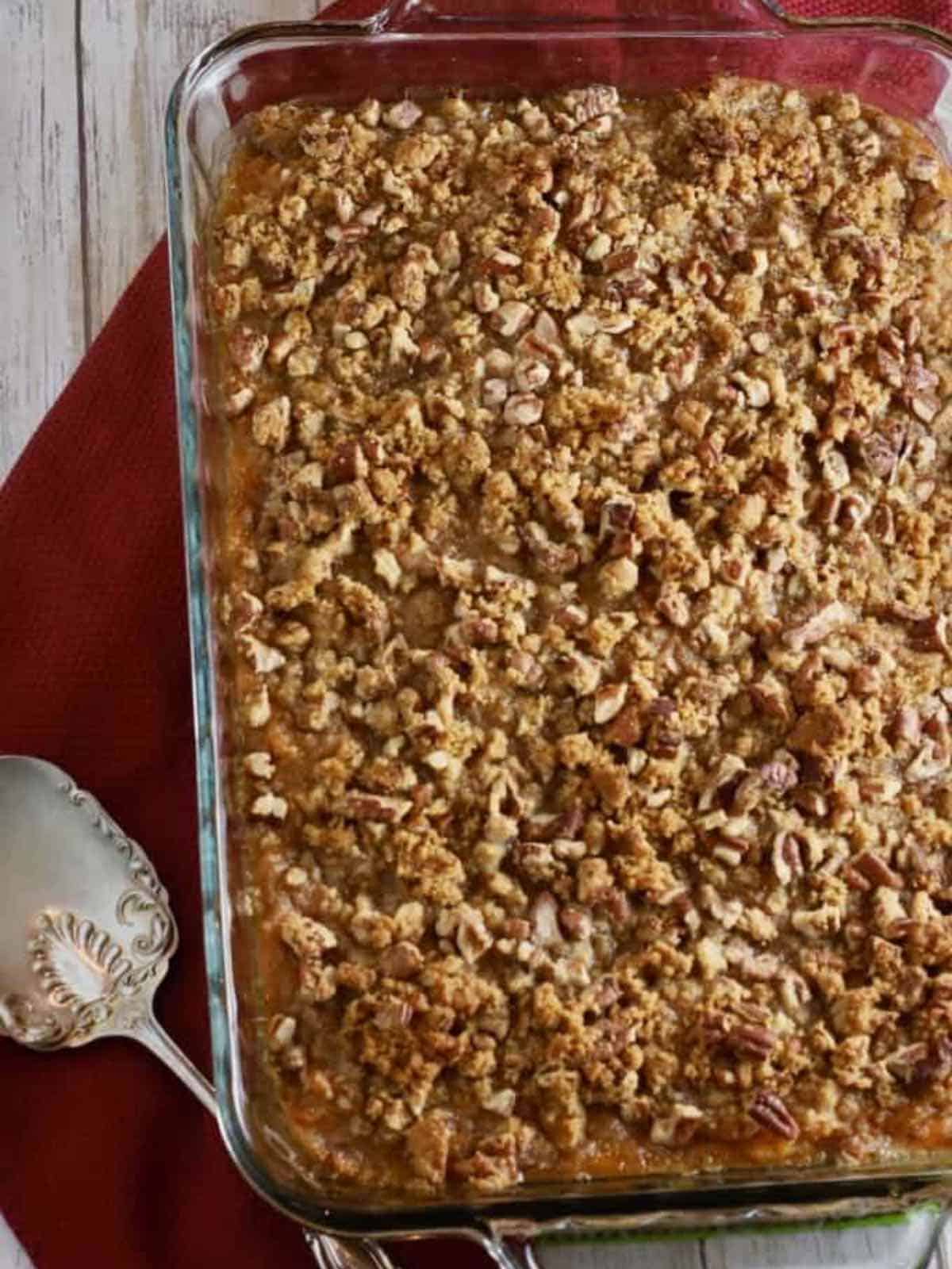 A sweet potato casserole topped with pecans in a rectangular glass baking dish.
