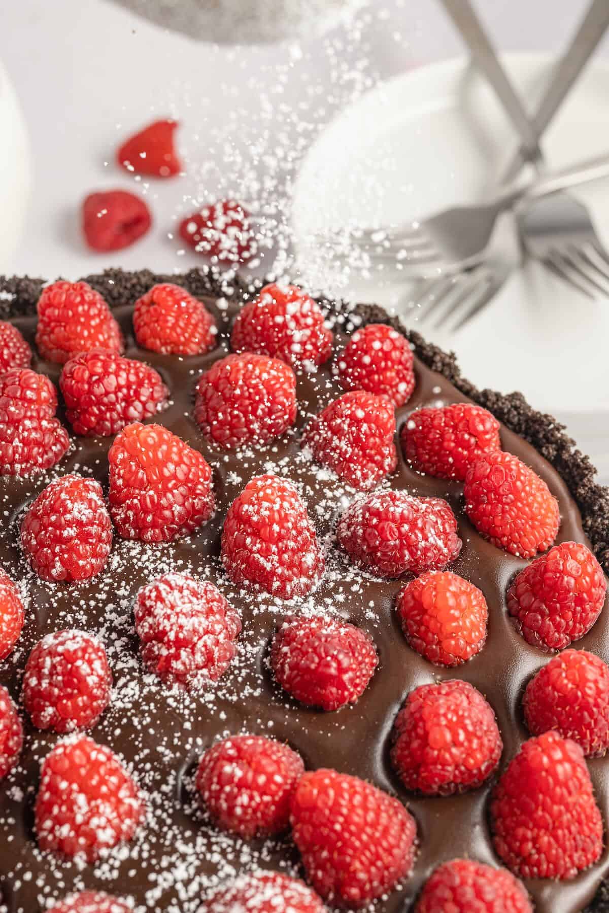 Dusting a chocolate raspberry tart with powdered sugar.