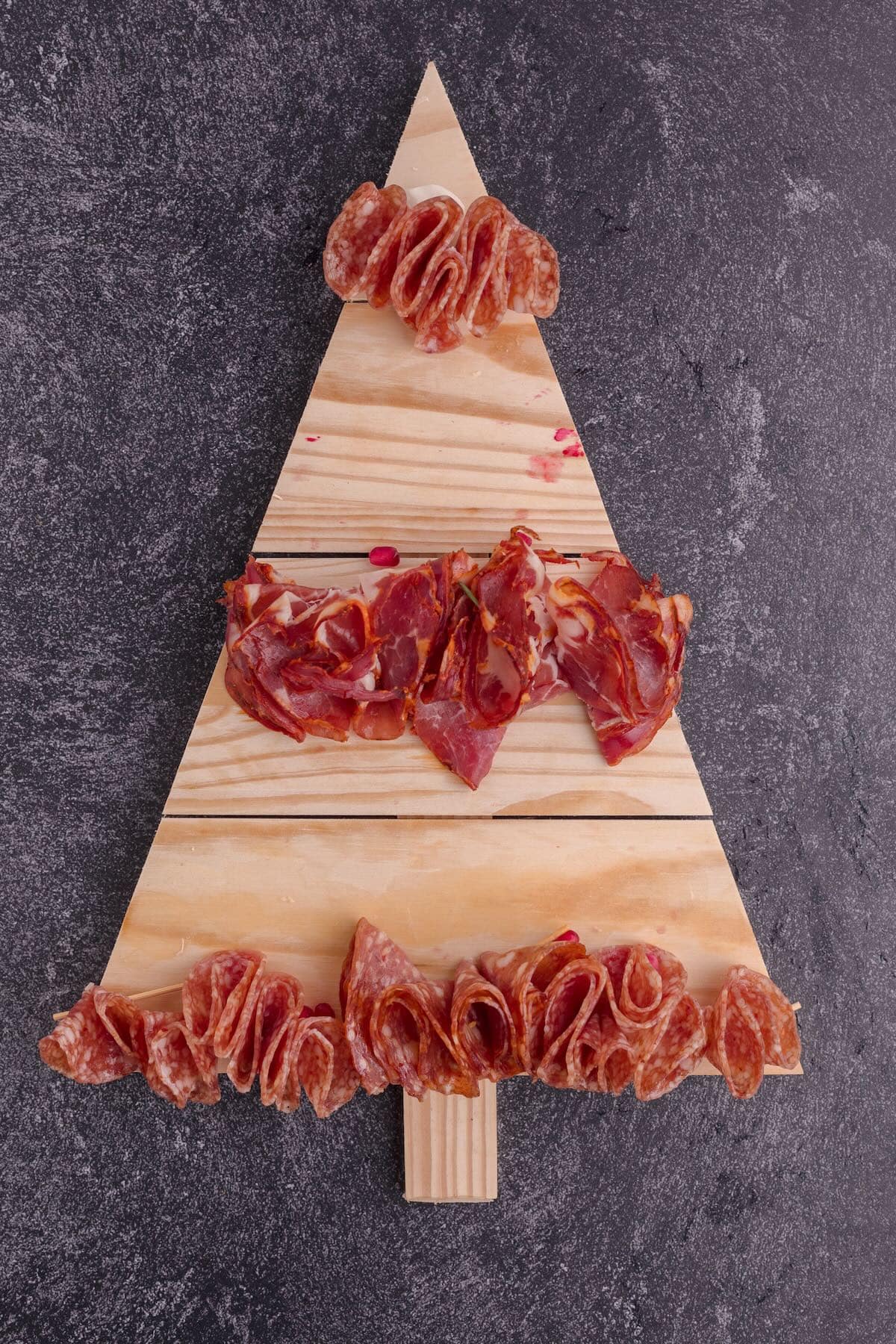 A board cut into the shape of a Christmas tree with three rows of folded meat. 