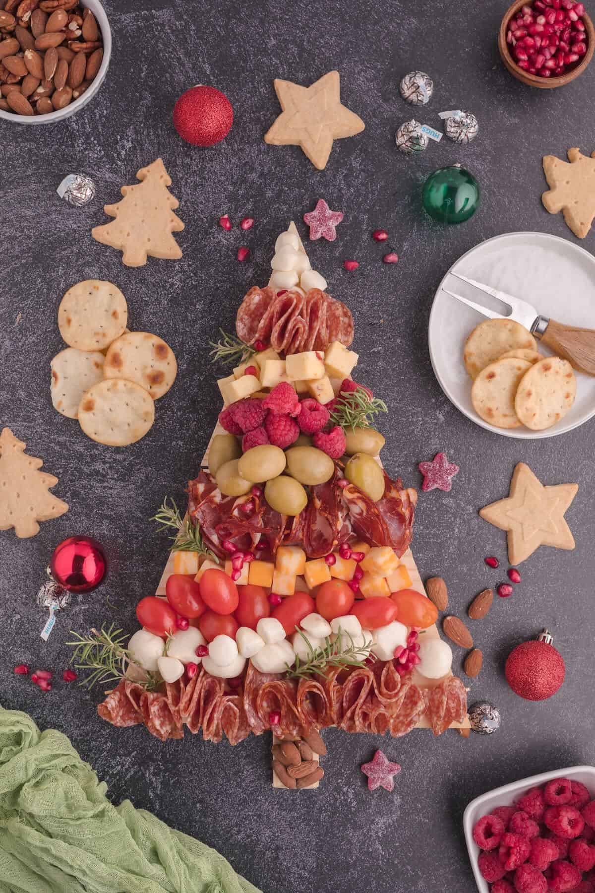 A Christmas tree charcuterie board full of meats, cheeses, nuts, fruit and vegetables,