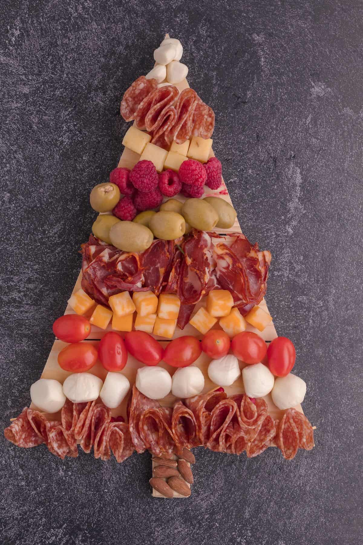 A charcuterie board shaped like a Christmas tree full of meats and cheeses. 