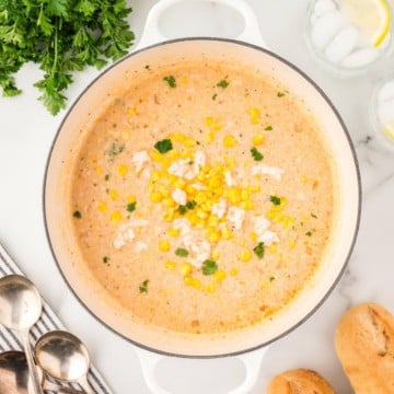 Corn and Crab Bisque in a white Dutch oven garnished with parsley.